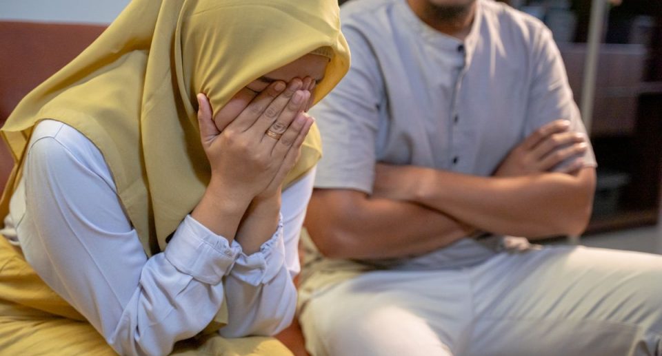 Couple arguing, man with crossed arms, woman with head in hands.